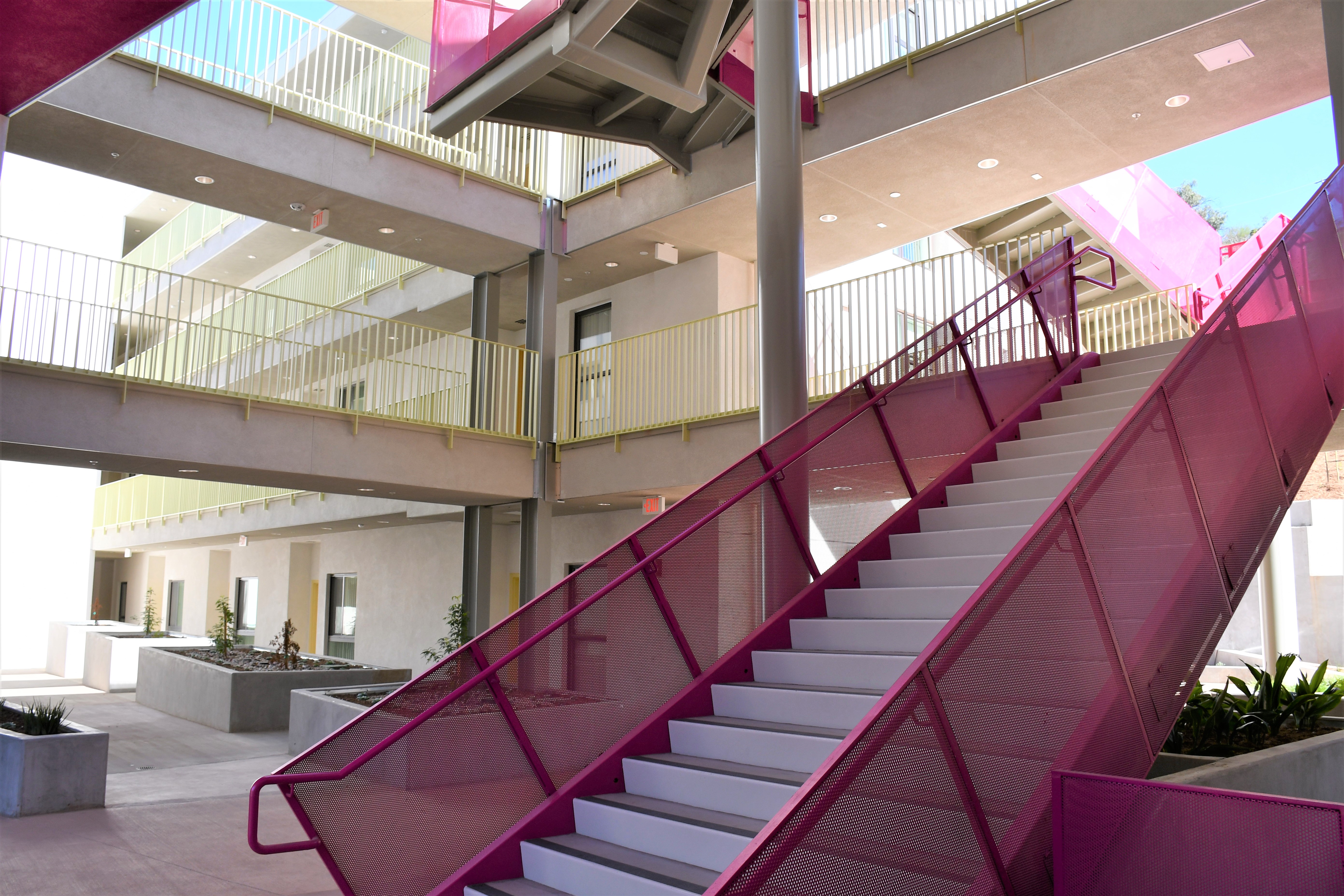 Purple stairs lead to the higher levels of the property. Upper levels have green railing. Ground floor has planters on the far end.