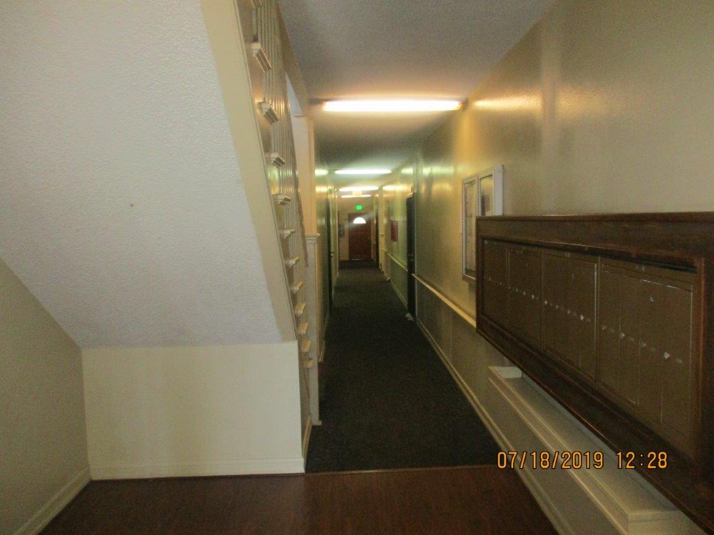 Concord A&B interior hallway. To the left are stairs leading up to next floor. To the right there is a long hallway with bulletin board near entrance and mailboxes.