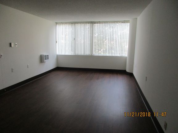 Inside view of the bedroom with white walls and brown wood floor