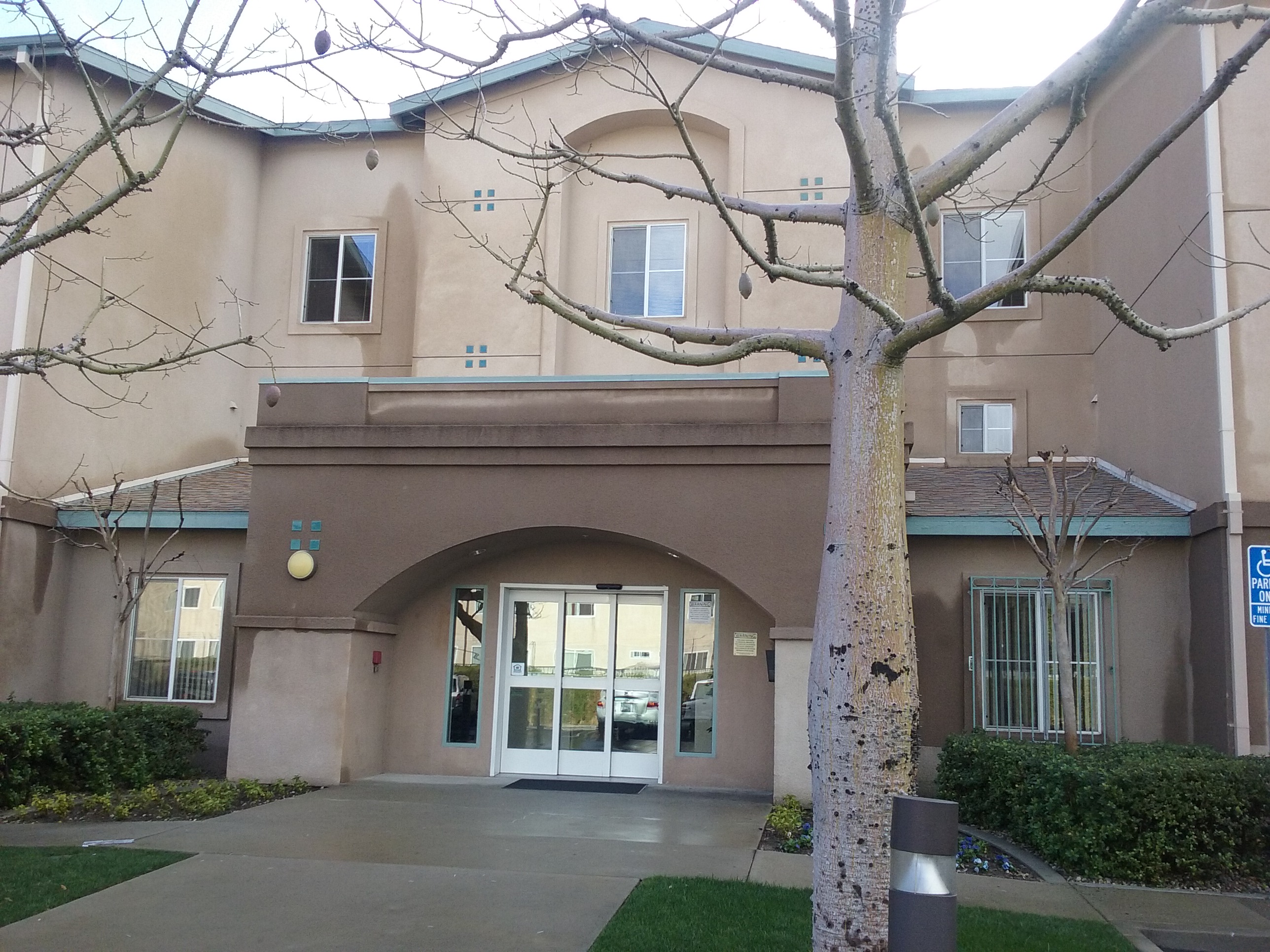 Front view of building with well maintained walkway. With moderate 
grass, trees, and bushes