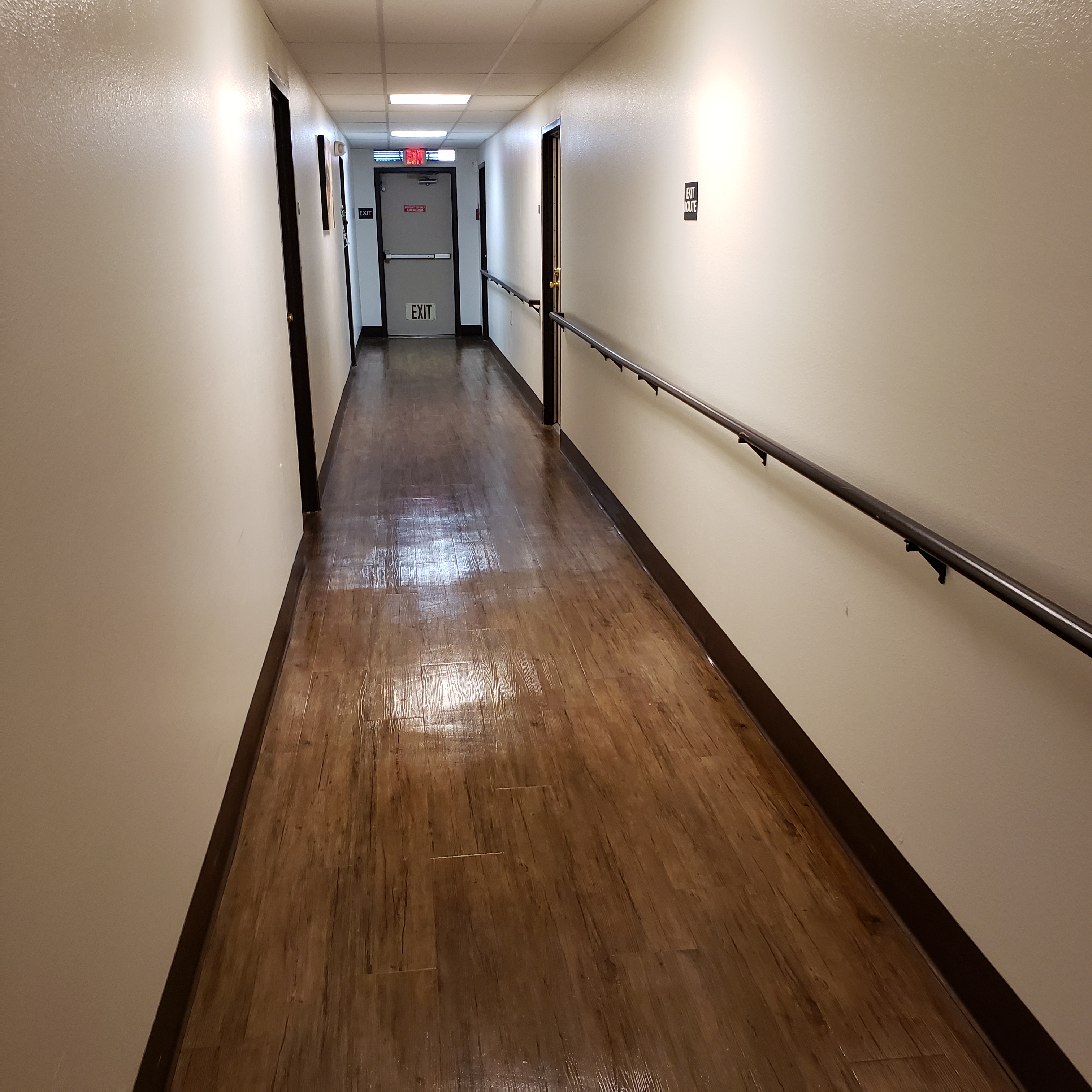 Image of tres lomas garden apartments hallway. long hallway with handrails along one side of the all.