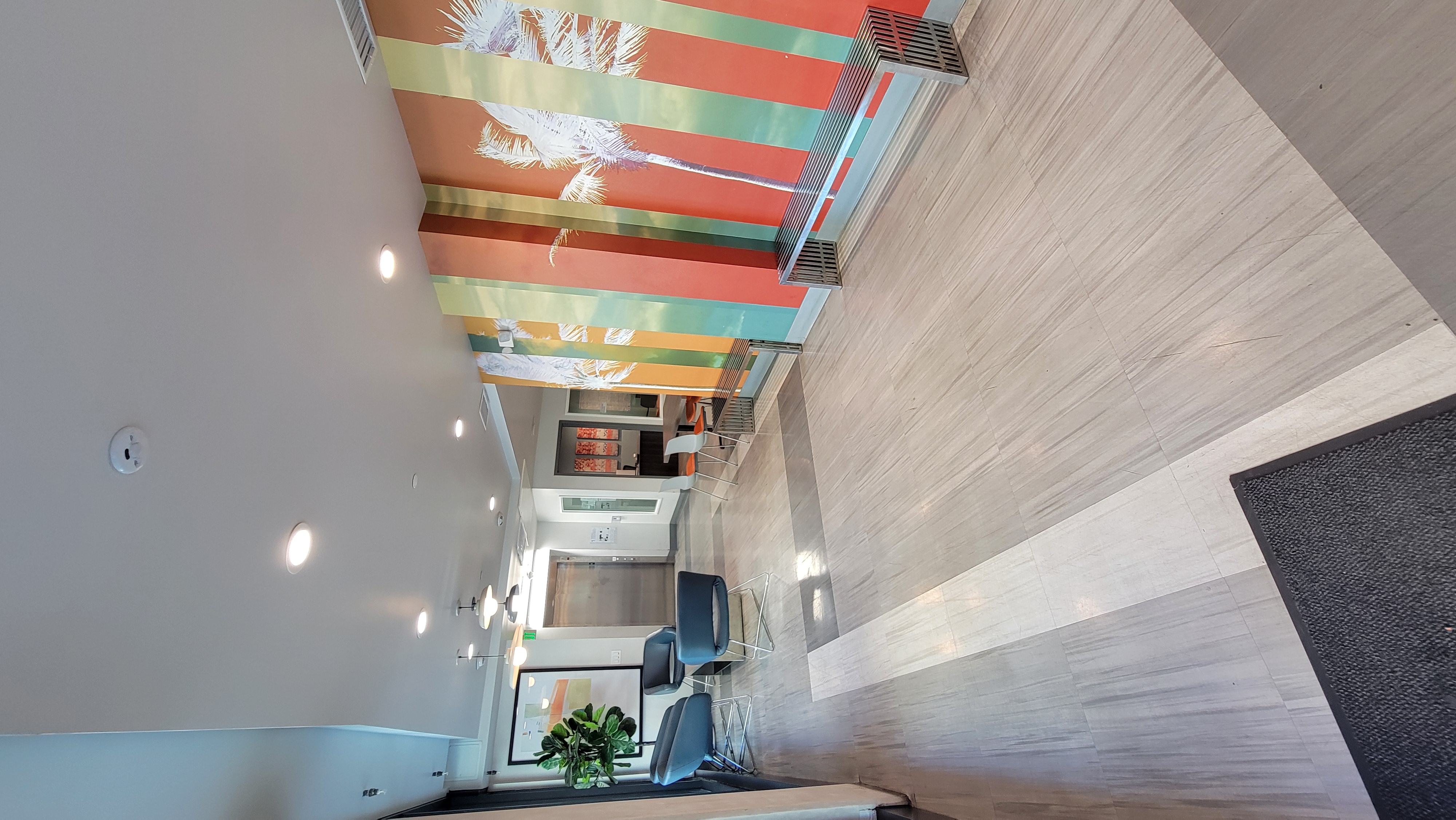 Lobby with seating next to window facing the street. A table with chairs for sitting is next to an interior wall.