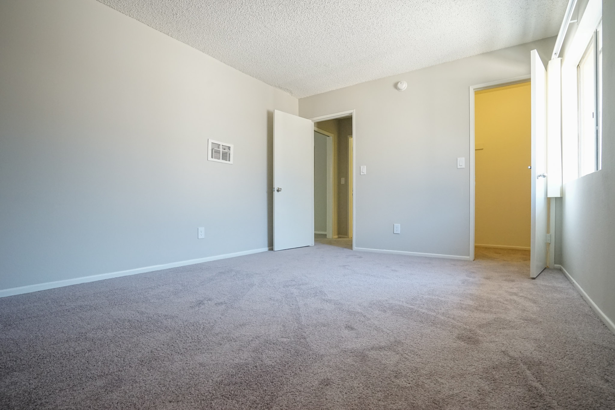 View of a bedroom with carpeted floors. Room has a window with blinds and a closet with a door.