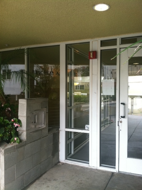 Front glass door view, call box on the left side, plants on the left side.