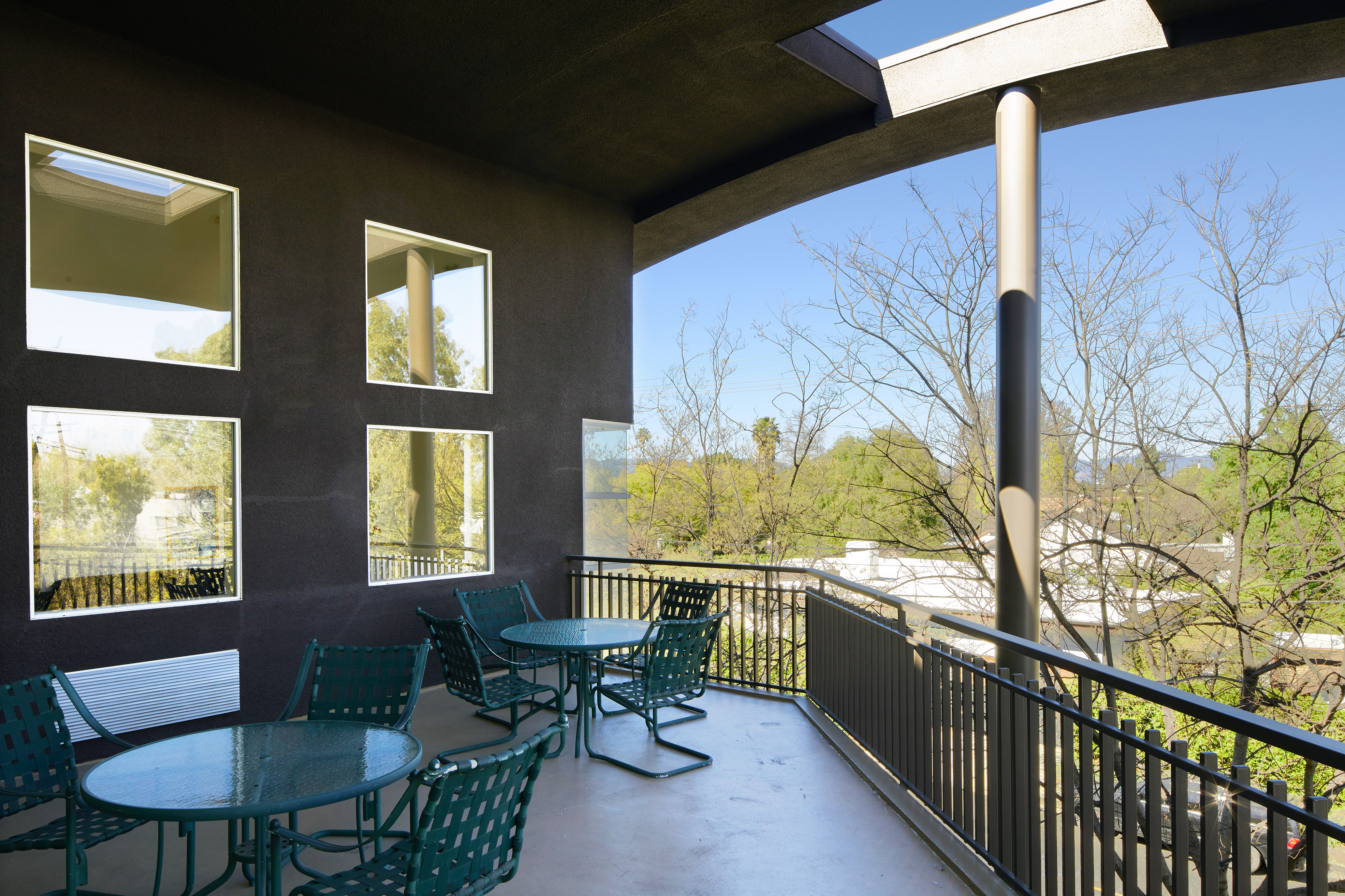 Exterior view of a patio at Noble Senior Housing with round tables and chairs