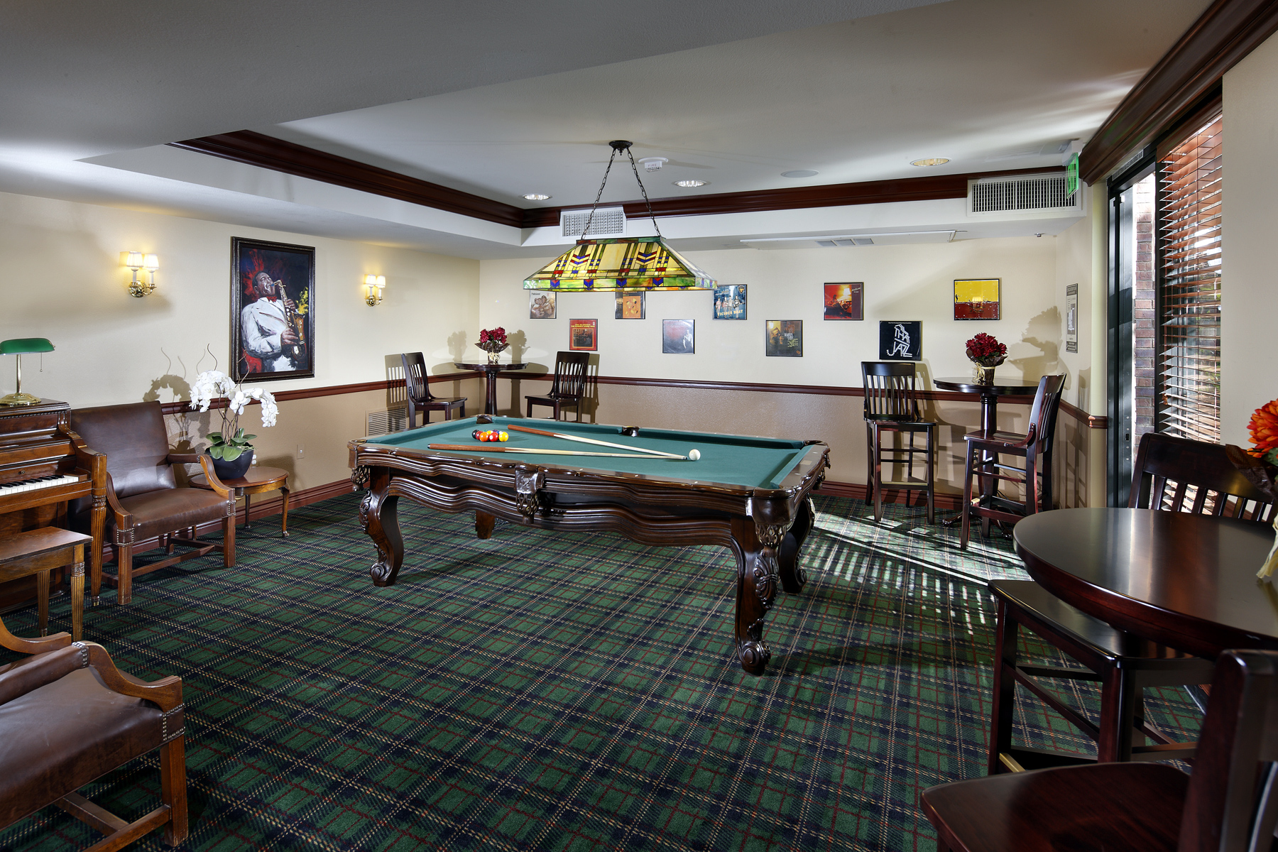 Rittenhouse billiard room. Pool table located near center of room. seating and tables along the walls of the room. large brown piano against wall. Decorative photos on the walls.