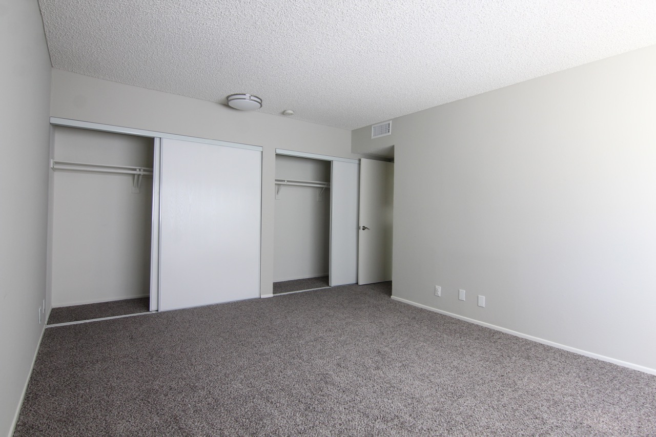 Different angle of a bedroomn with two closets. Floor is carpeted.