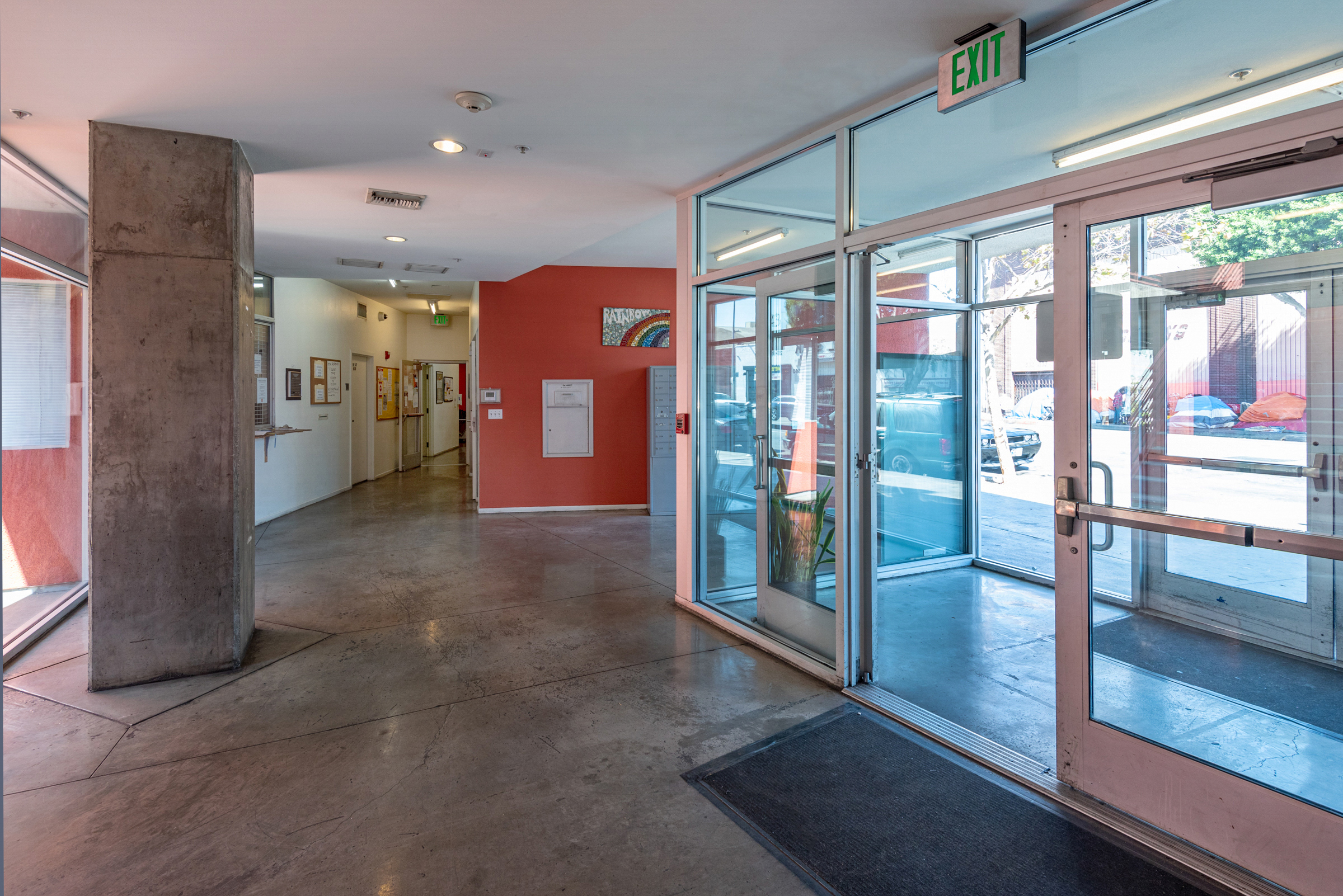 View of an entrance to the building, glass doors, and a concrete pillar.