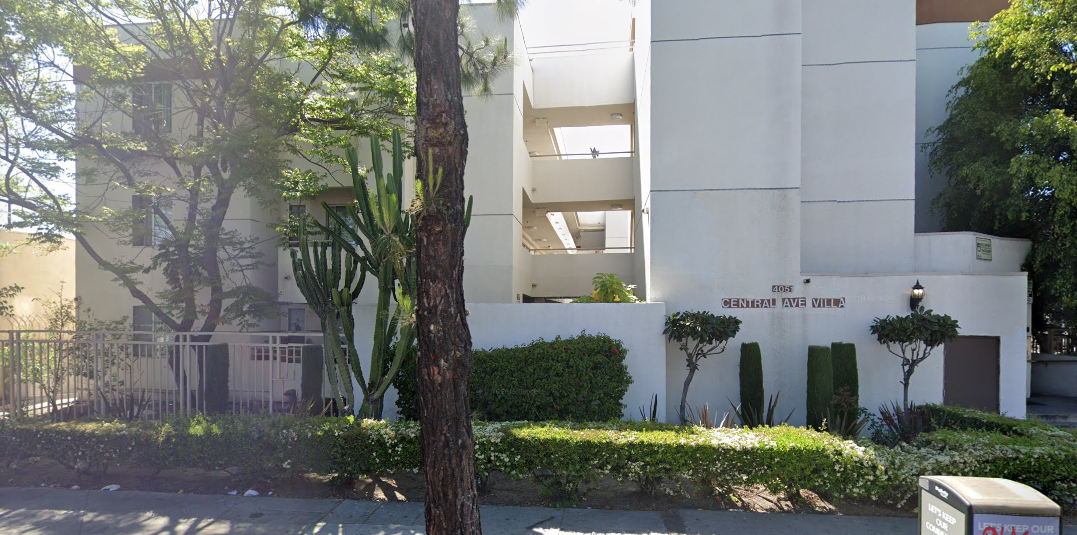 Street view Central Avenue Villa Apartments, 3 story white building with a row of bushes and trees in front of building