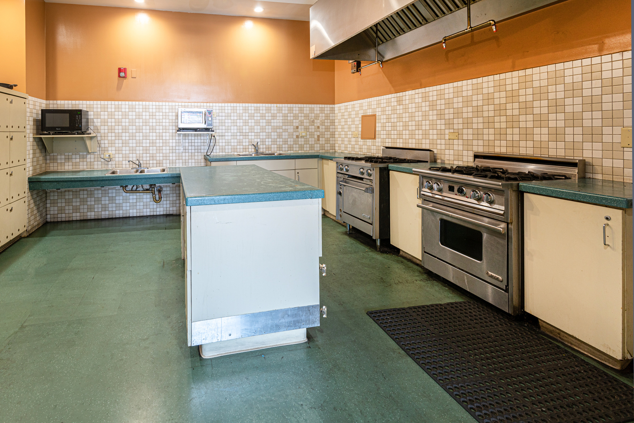 Interior view of the Community Kitchen for the Produce Hotel, 2 stoves, center island, microwave and sink.