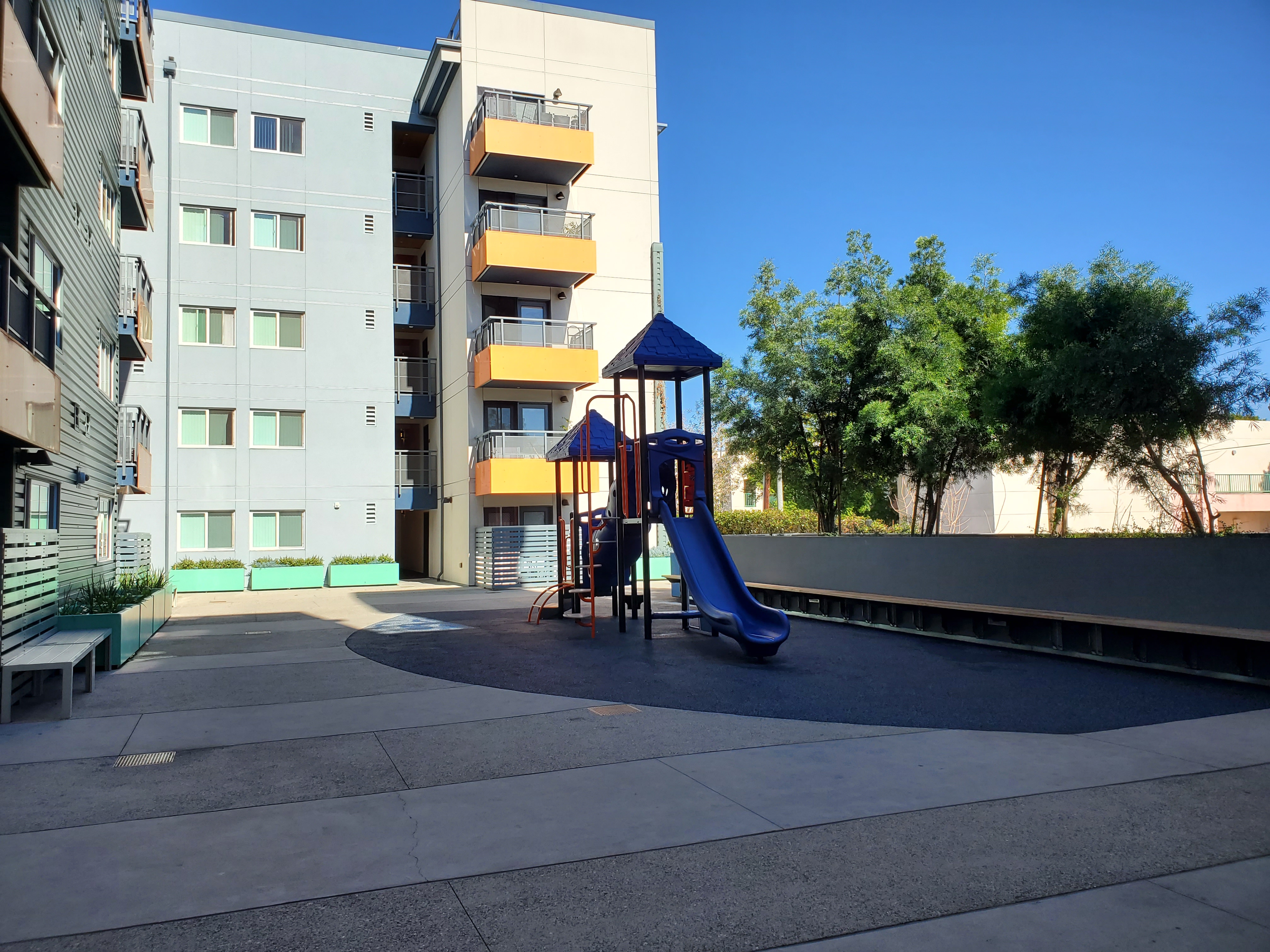 Exterior view of the Selma Community Housing, 5 story building with a small playgroung
