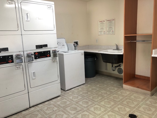 Interior view of a laundry room at Wisconsin 3 Apartments, five machines with a sink with counter space