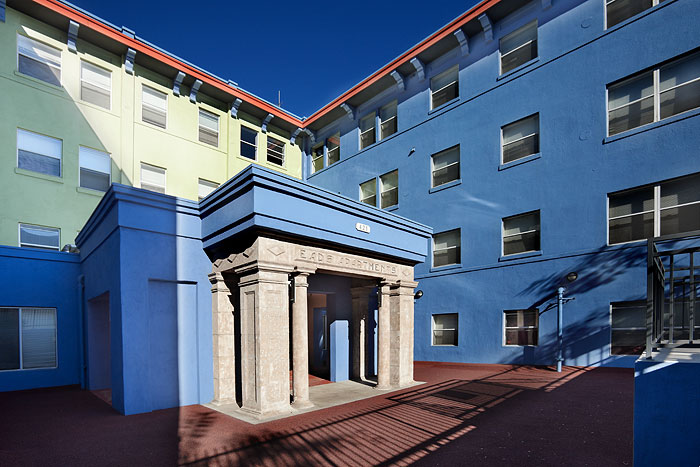 View of an entrance to a four story building that is lime green and blue. Entrance is ground level and has pillars on the sides.