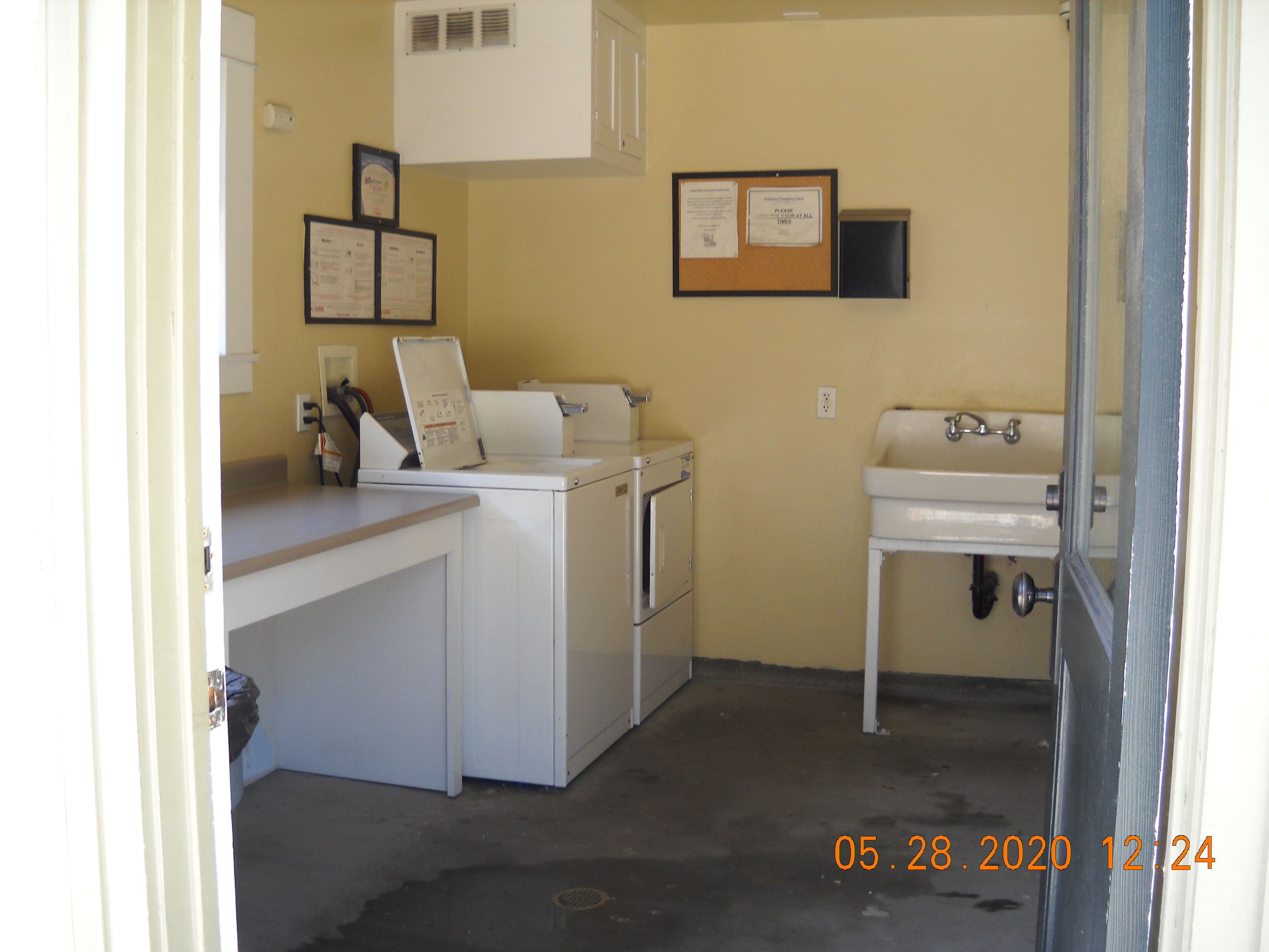 Laundry room with a washer and dryer, a sink, and a folding table. On the walls there are signs.