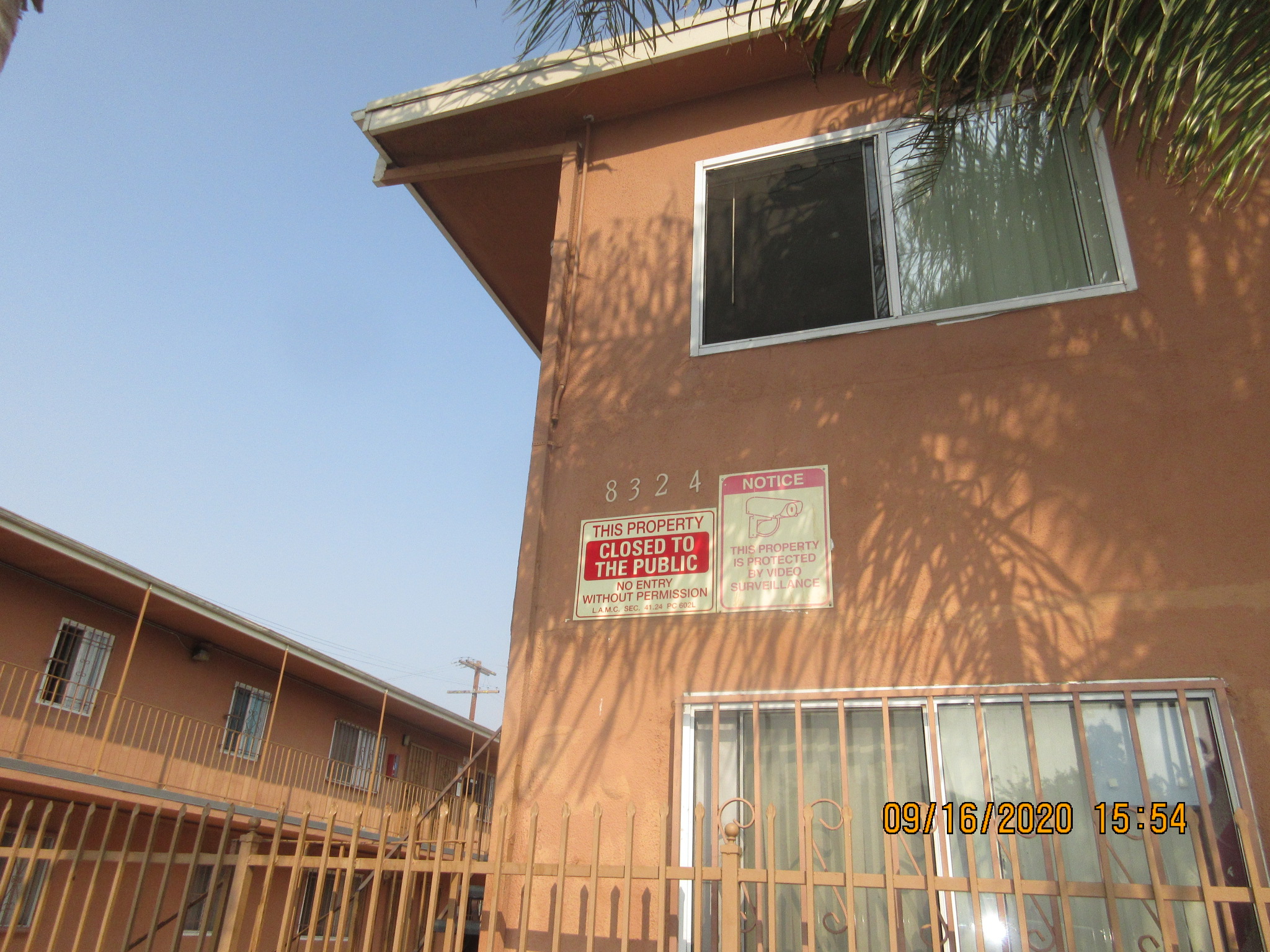 Corner view of a two story building, building number and management signs on the wall.