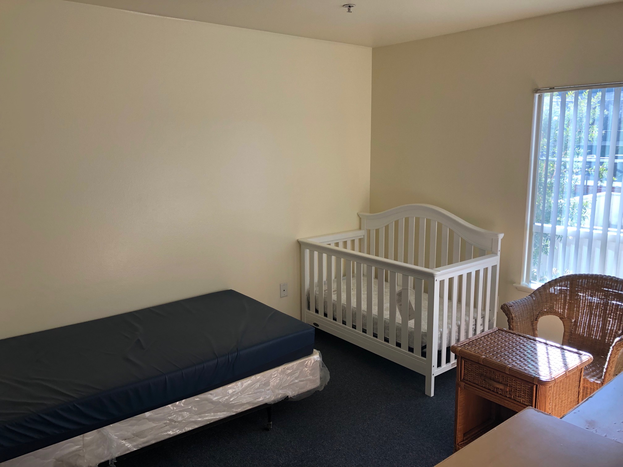 Bogen 2 Bedroom with twin bed and baby crib near the foot of the bed.  Wicker table and chair set near the window