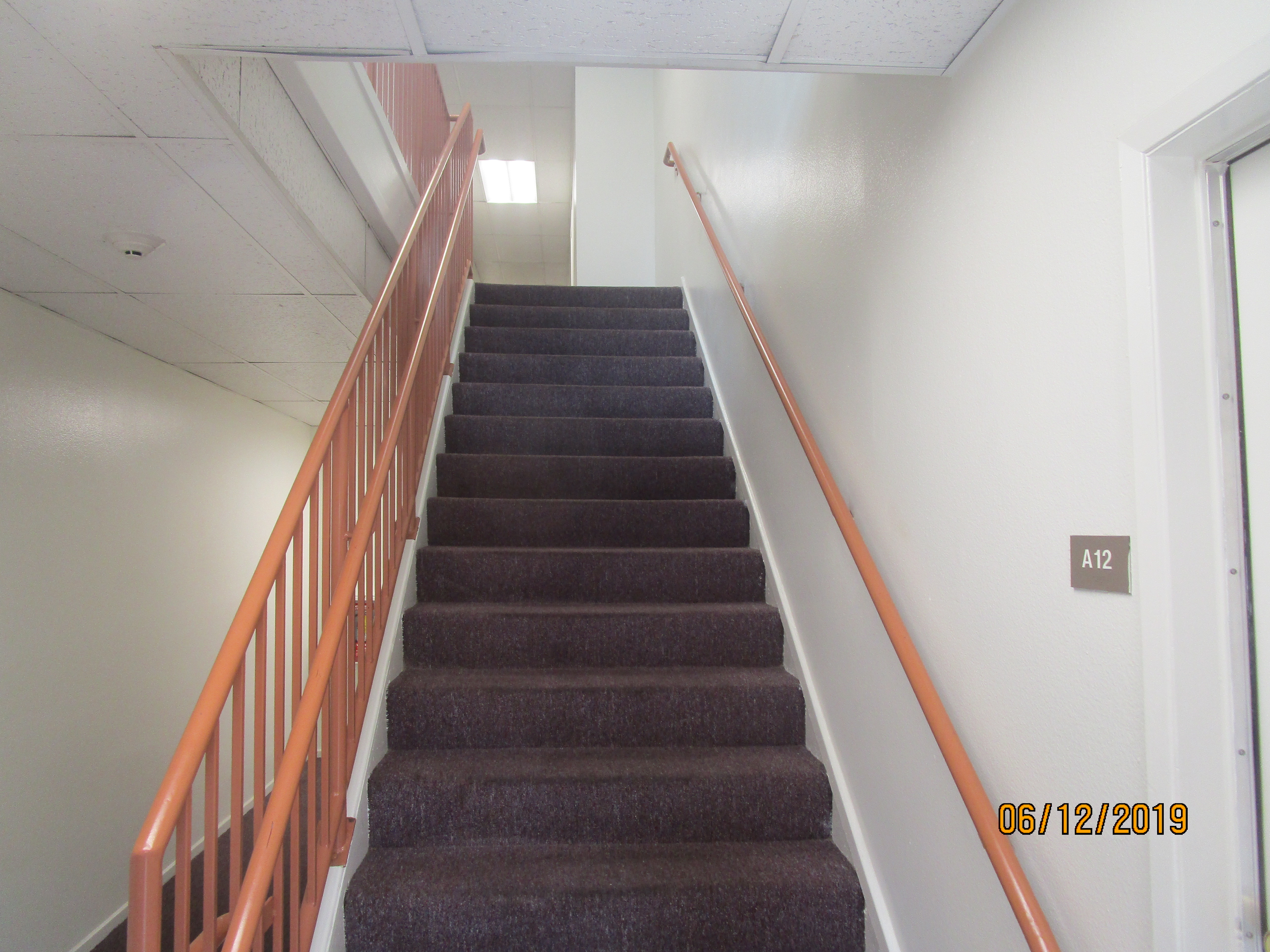 View of the carpeted staircase with orange handrails