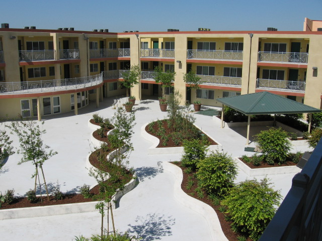 Image of yellow 3 floor building and courtyard with planted areas