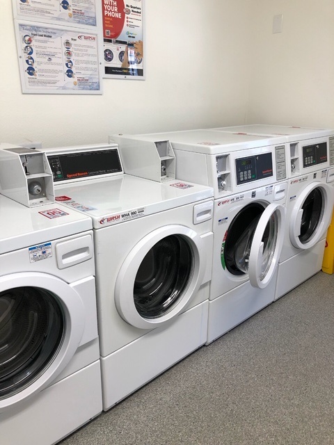 Laundry room with two washers and two dryers adjacent to one another. Instructions on how to use machineray are posted on the wall.