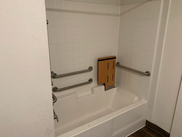 View of shower tub with grab bars and foldable bench.
