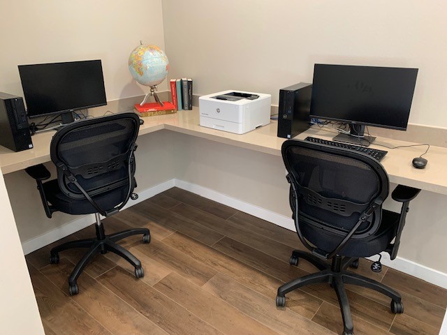 Computer area with two desktops and chairs.