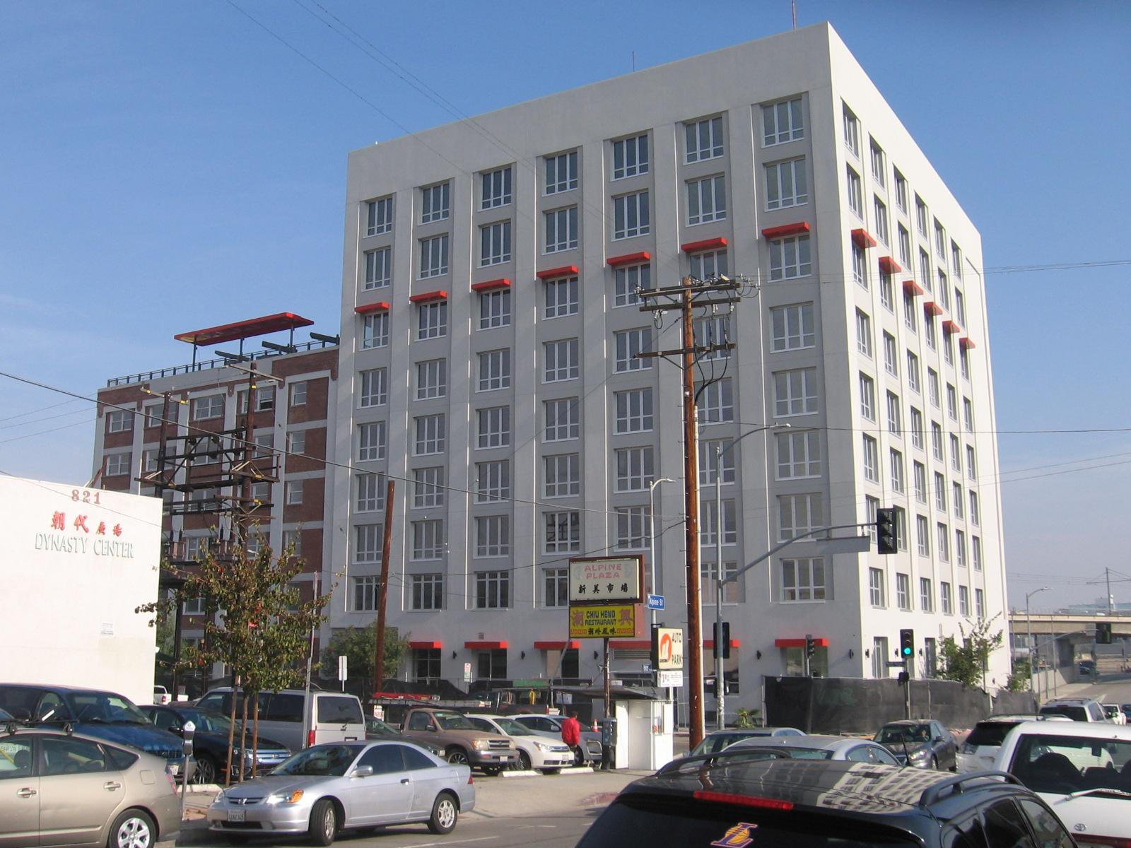 Street view of a tall eight story building in grey color. In addition of a five floor brown building on the right