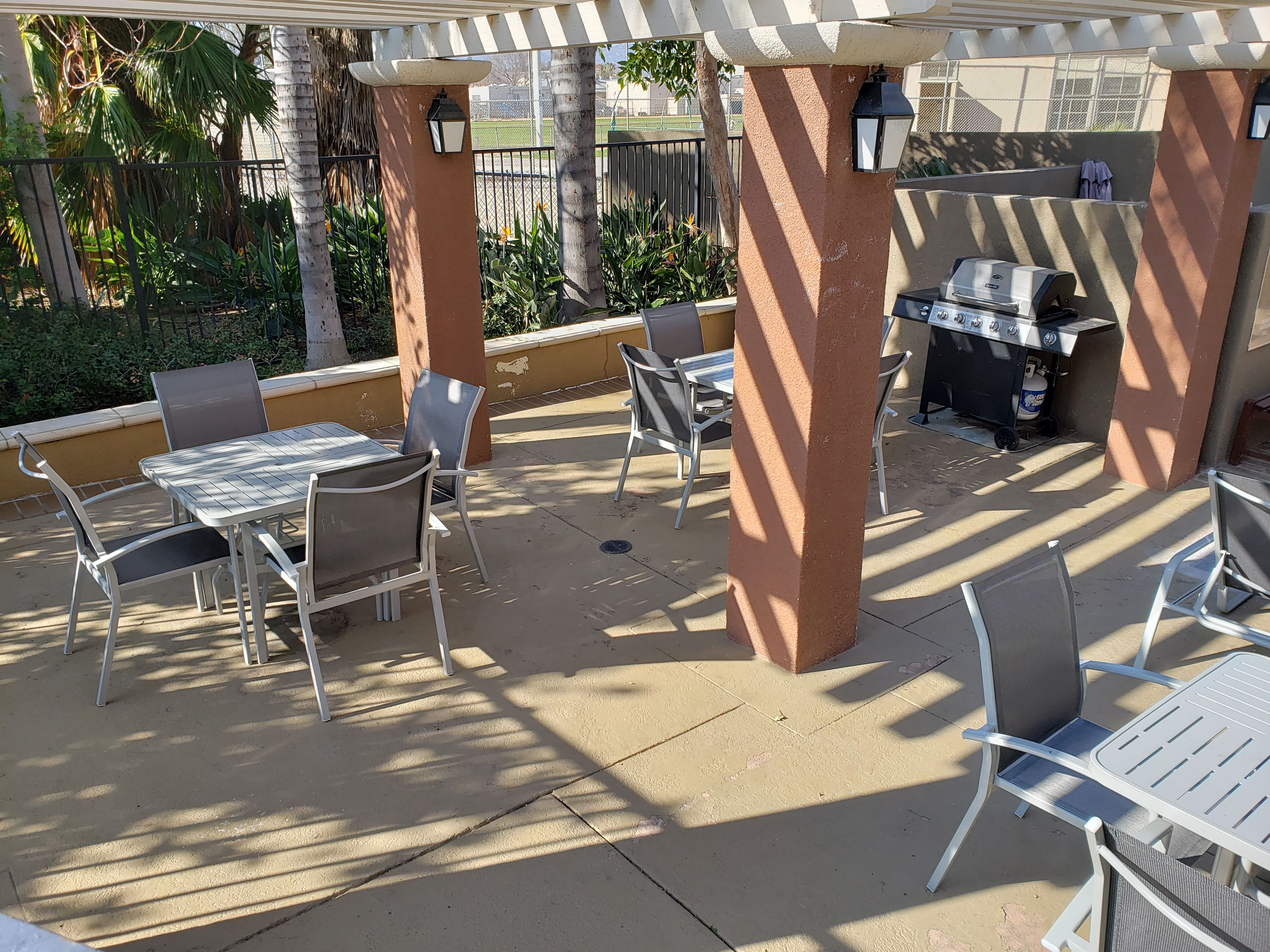 Image of vintage crossing senior apartments bbq area. Area is fenced off. bbq grill available under gazebo with tables and chairs. raised plant beds along fence