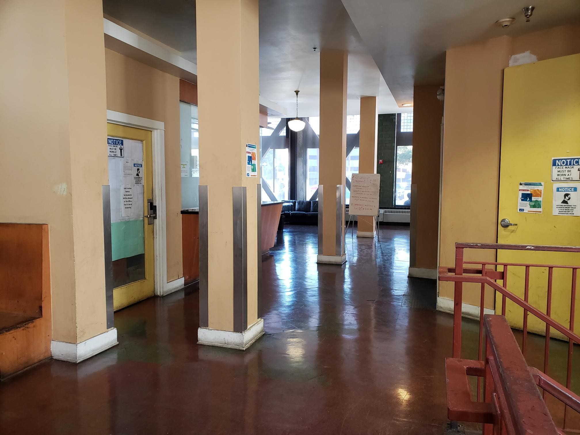 View of a lobby, burgundy floors, four yellow pillars.