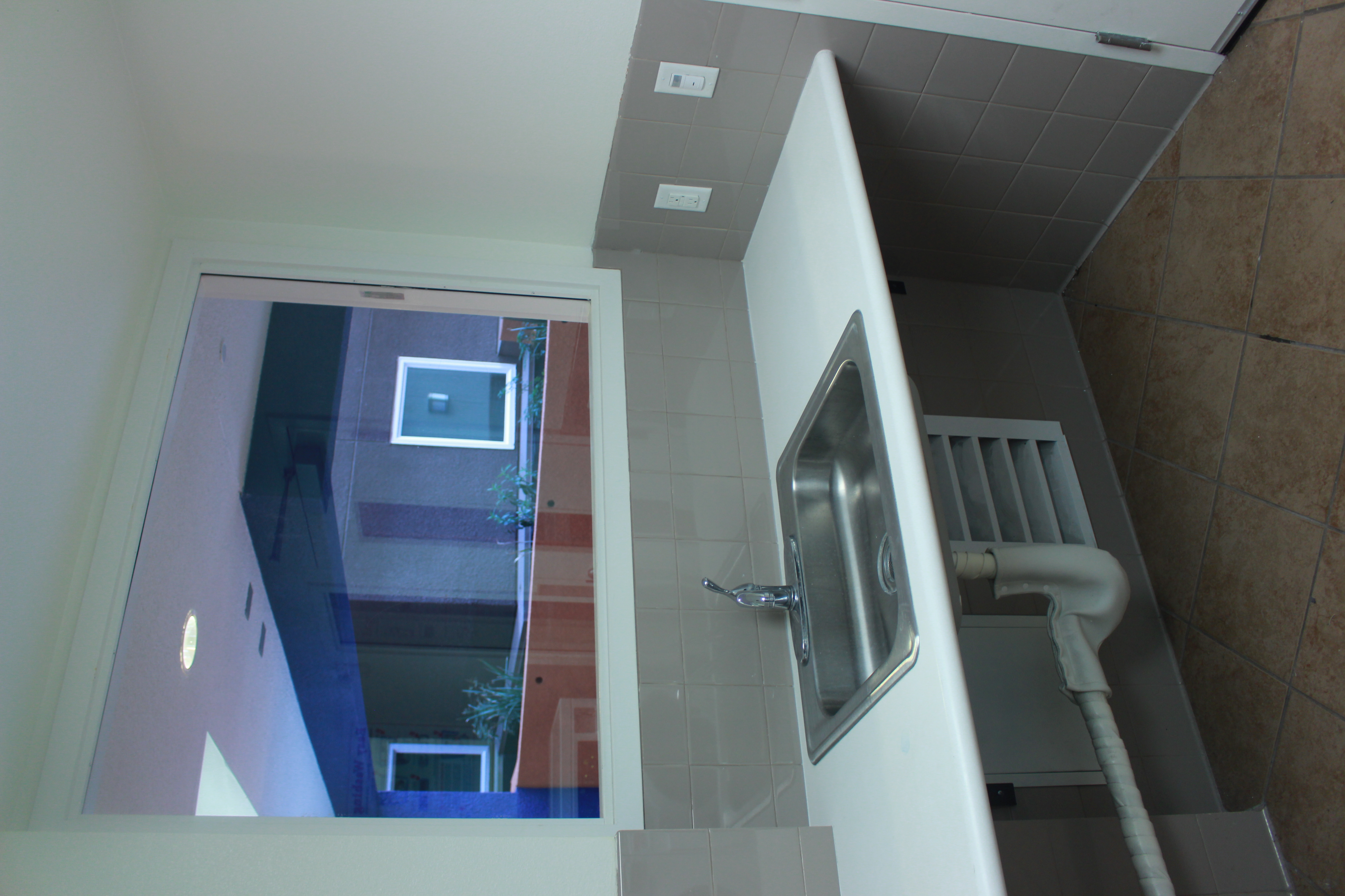 Front view of the laundry stainless steel sink, a see through window, an outlet switch on the right side.