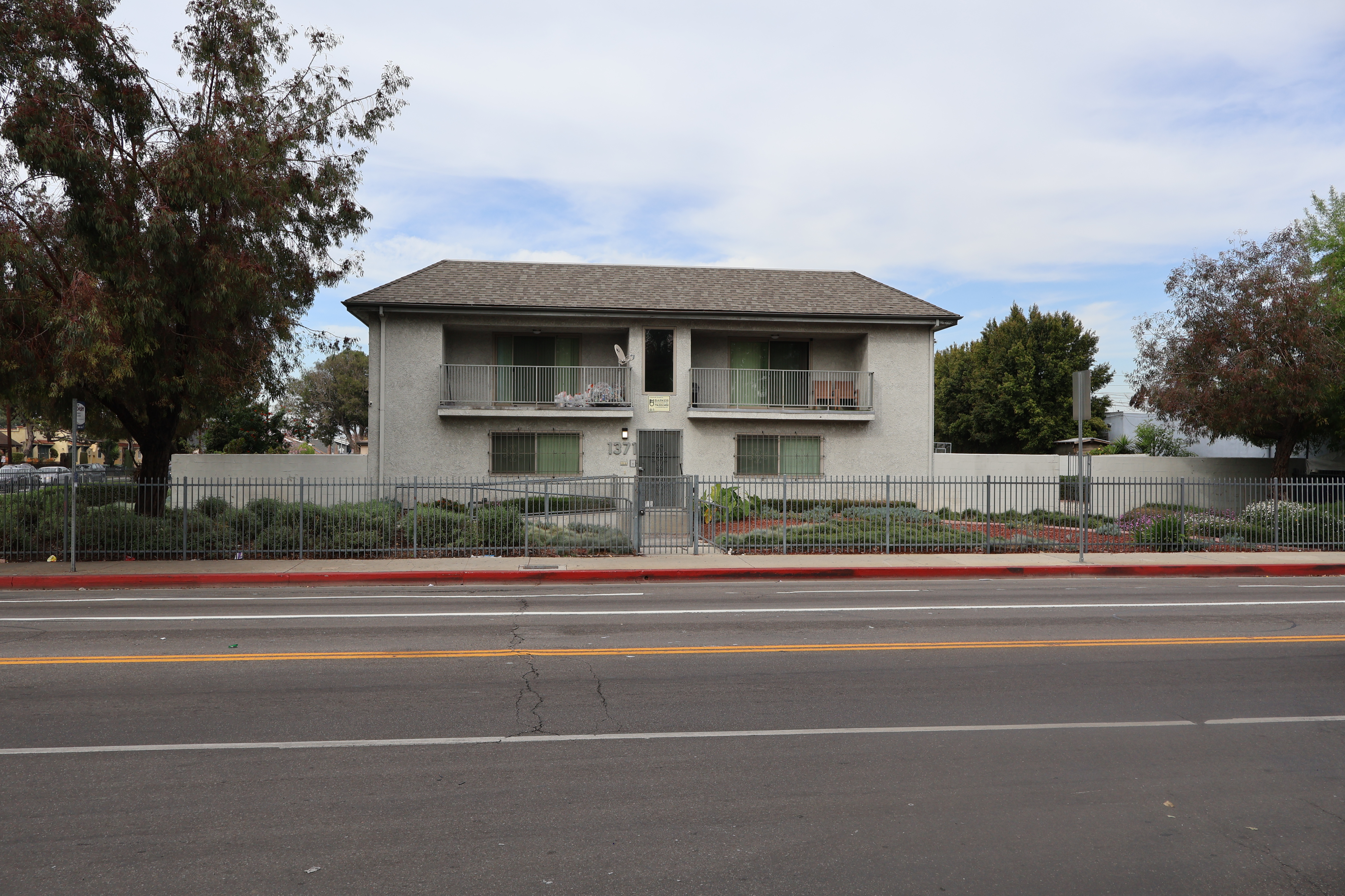 Image of front entrance of Watts Athens Preservations aka Normandie. Double story community with gated areas of plants and trees, balconies on front side