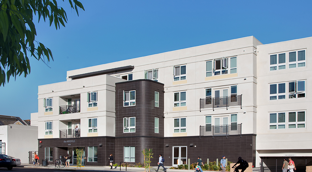 Exterior view of Agrgyle Apartments. 4 story building with the first level dark brown and the rest is off white.
