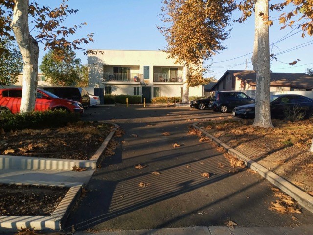 Image of street view of property, with trees and cars parked on the street