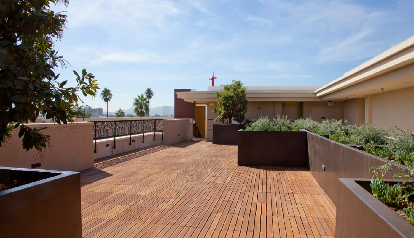 Deck Area on roof - seating, wood deck and planters, decorative metal railing view of several tall palm trees and a distant mountain