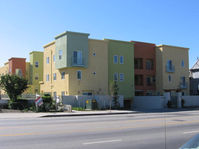 Colorful three story building with basement gated parking on premises.