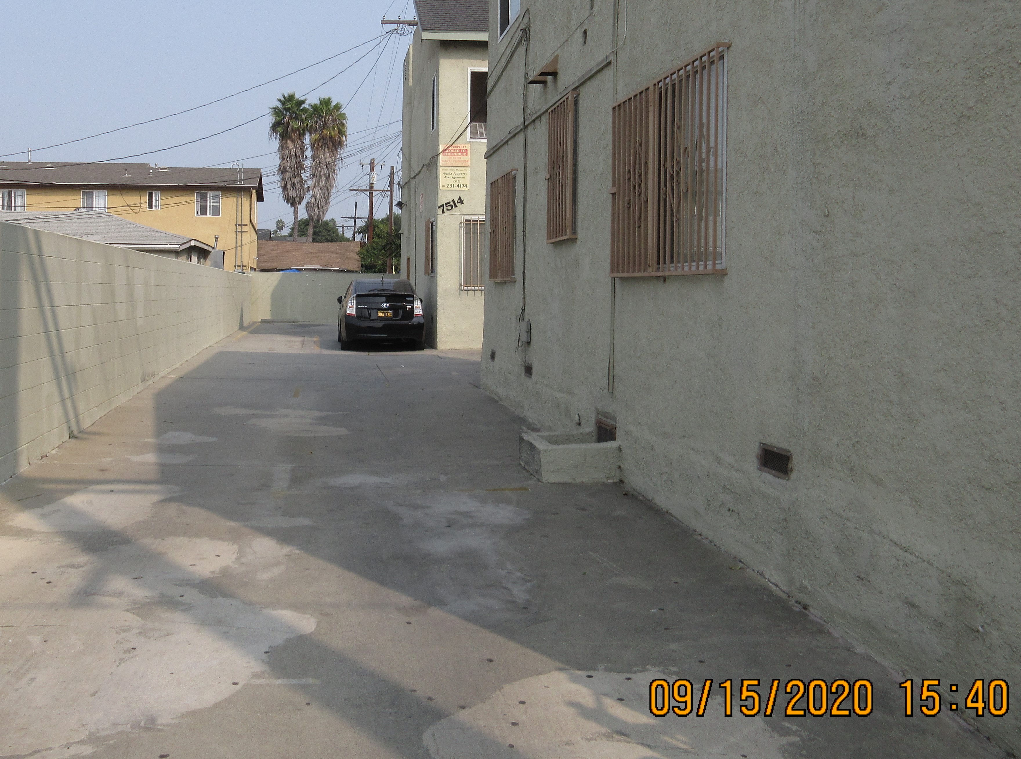 Side view of the building, wide concrete driveway, parked car.