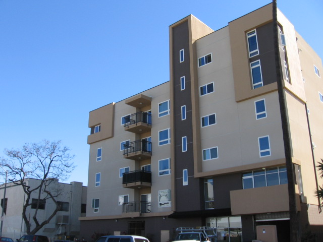 Front view of a four story building with balconies in brown color