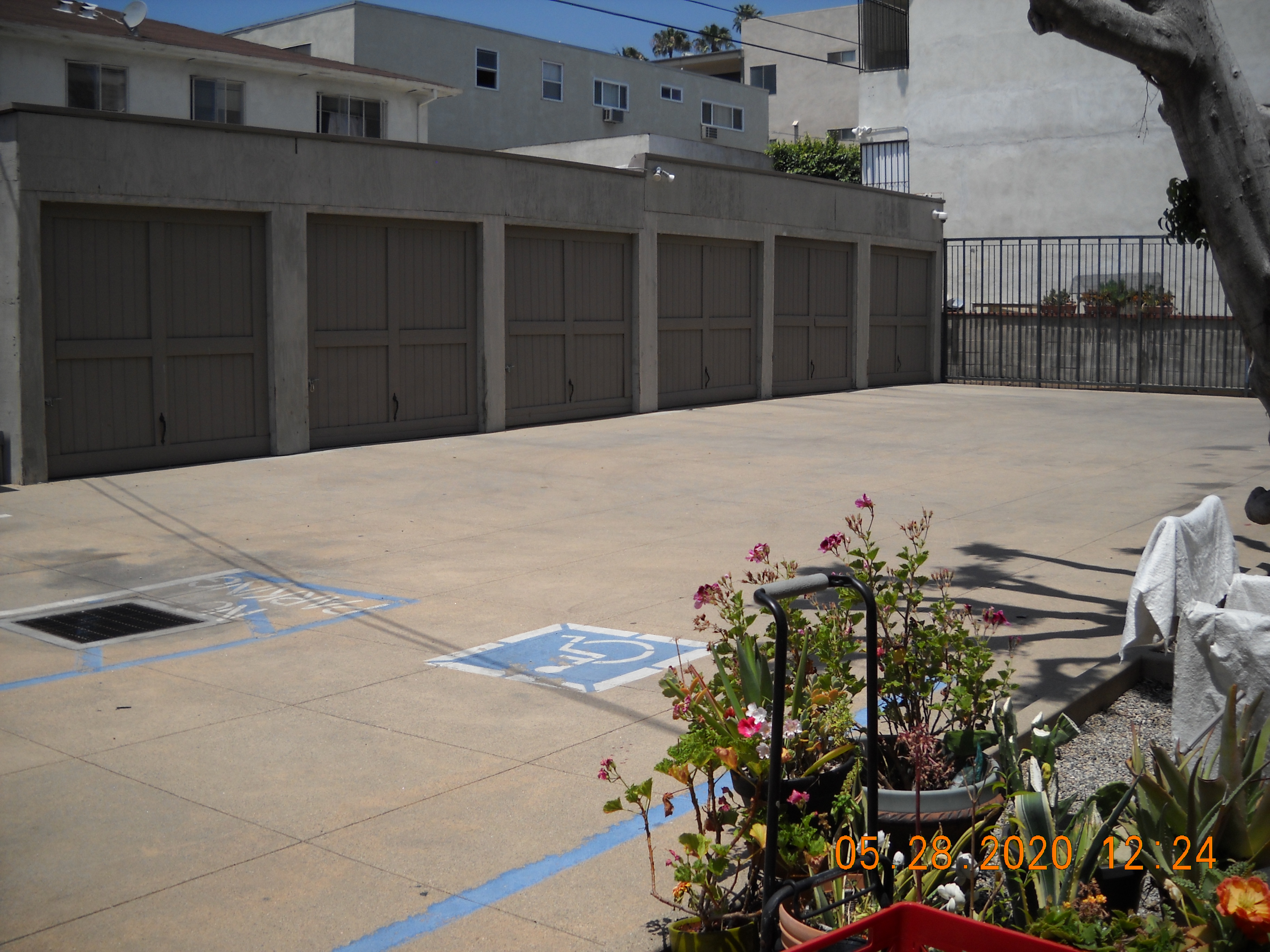 View of an outdoor parking lot with a regular and accessible space viewable. There is a one story with multiple closed storage spaces.