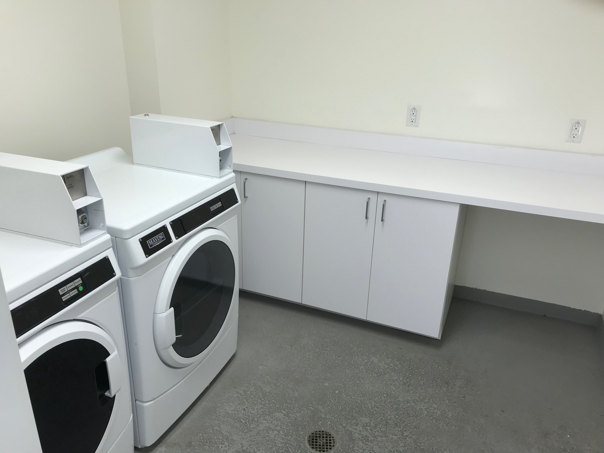 View of the laundry room at King 1101 Apartments showing two machines and a long counter with cabinets underneath