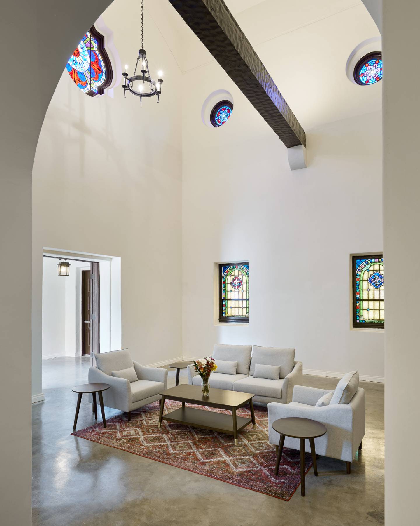 Photo of a common indoor sitting area in Washington View Apartments. Building has high ceilings and stained glass windows. Three couches are pictured.