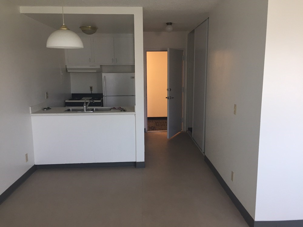 Interior view of one of the studio unit at E. Victor Villa. View 
from dining room area and kitchen that is seperated 
with a half wall. Small kitchen next the entry door of unit 
which inludes a fridgerator and oven. Above the oven and 
fridge there are