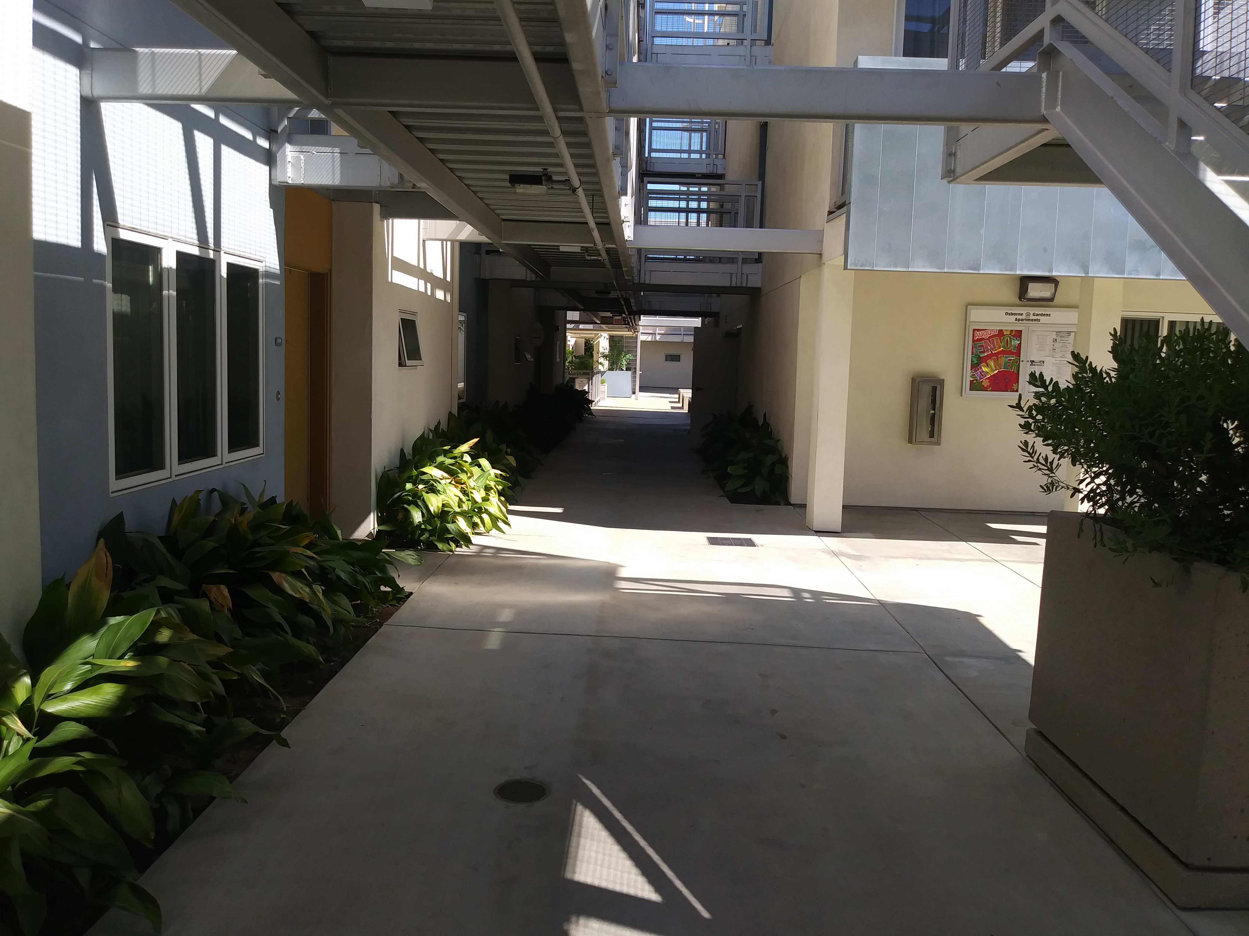 View of a corridor with plants on either side at Osborne Family Apartments