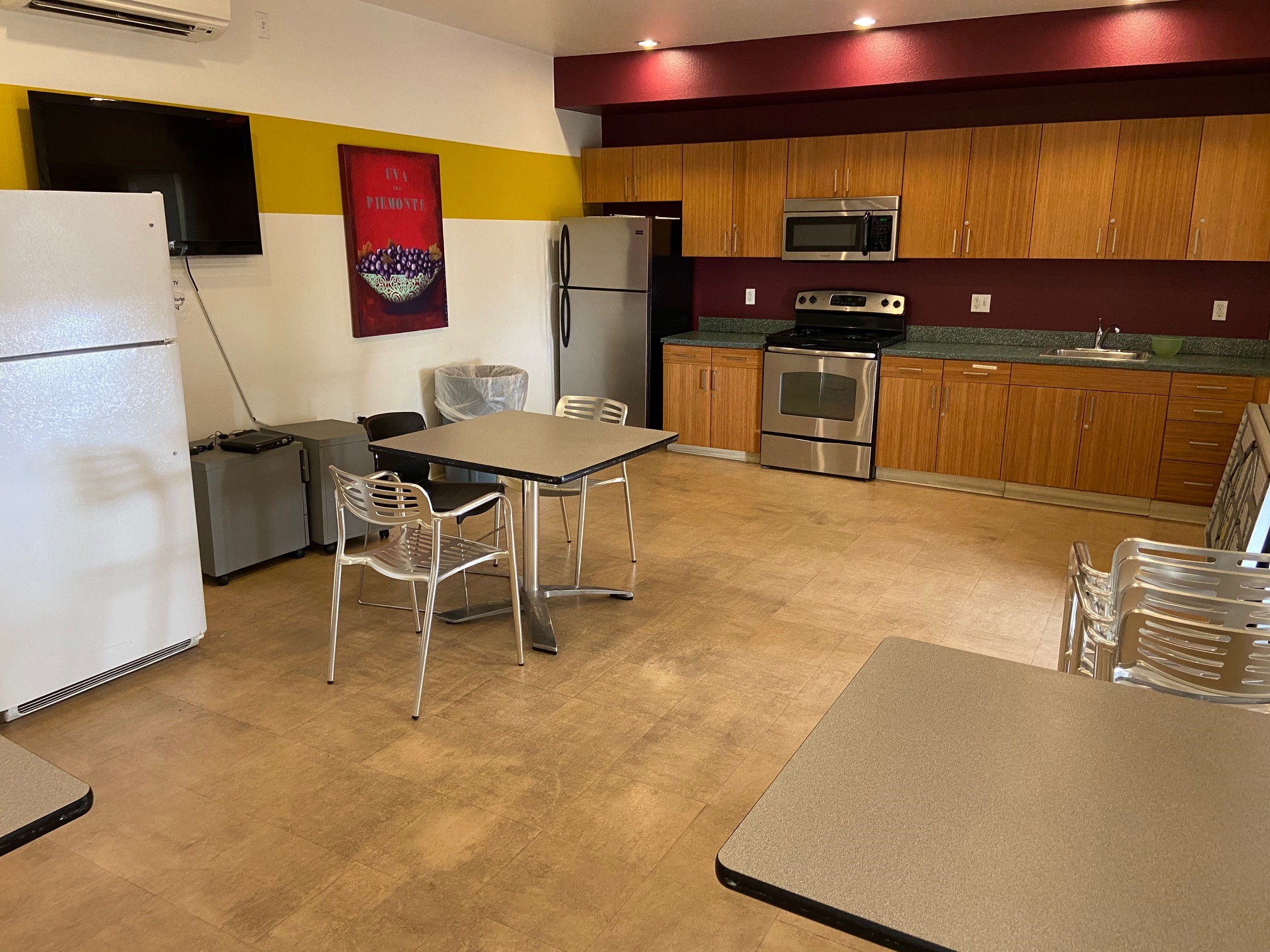 Interior view of a kitchen at Vendome Palms Apartments showing two refrigerators, stove, sink, tables and chairs