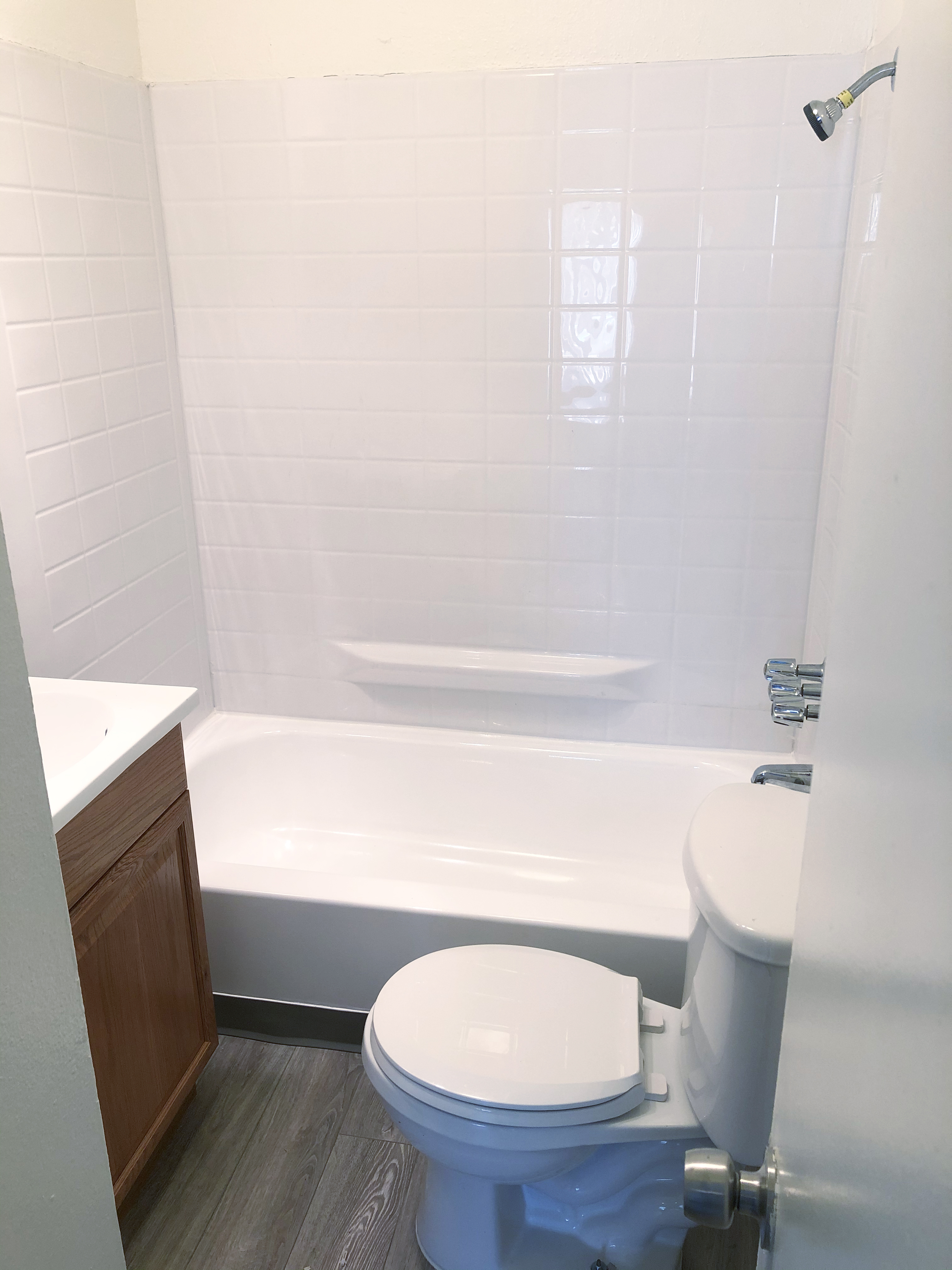Interior view of a restroom in a unit, showing a bathtub with a shower, toilet and sink.