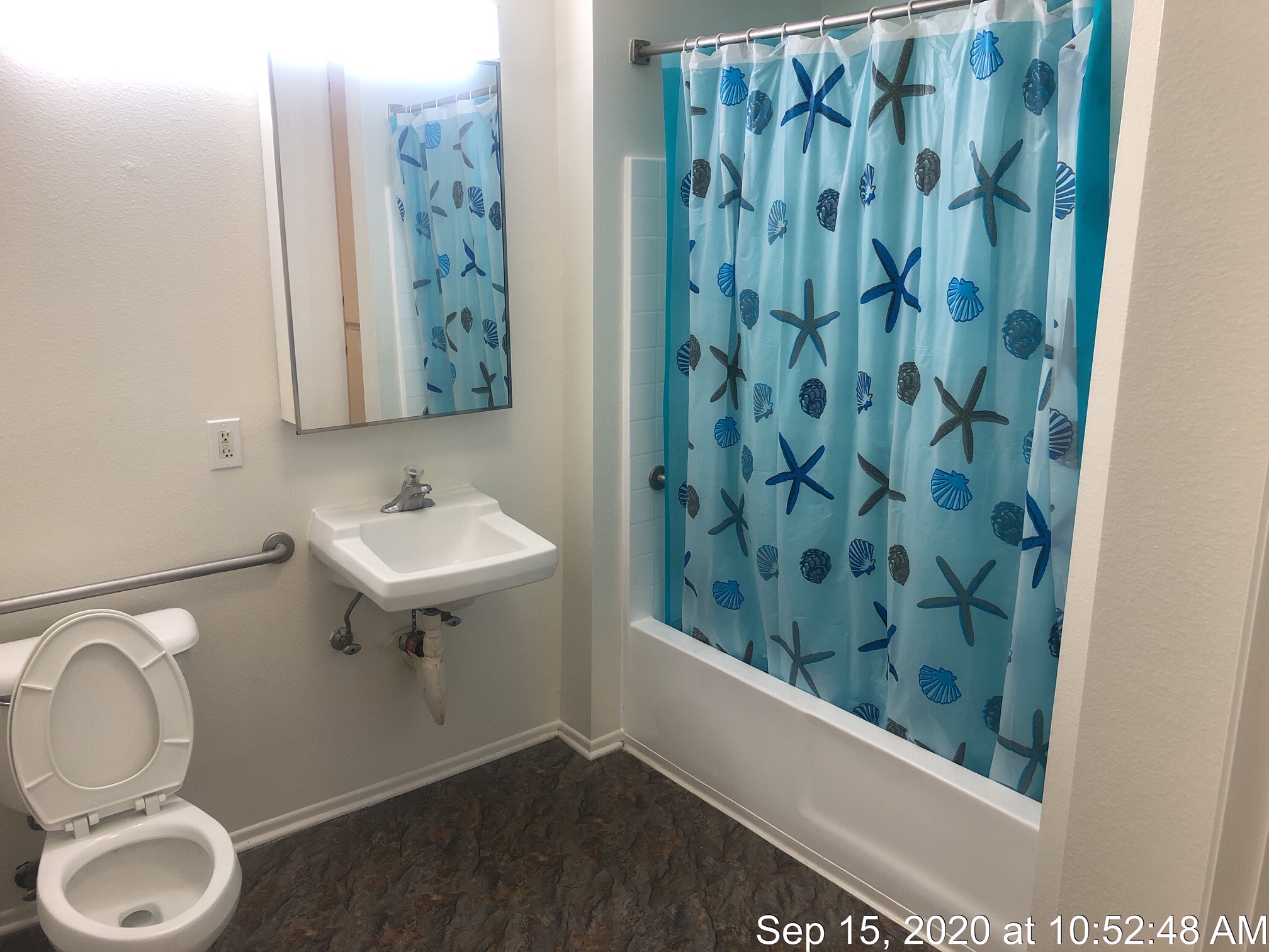 HFL Palms Court - View of a bathroom with a toilet, sink, medicine cabinet with a mirror and bathtub with a shower rod and curtain.