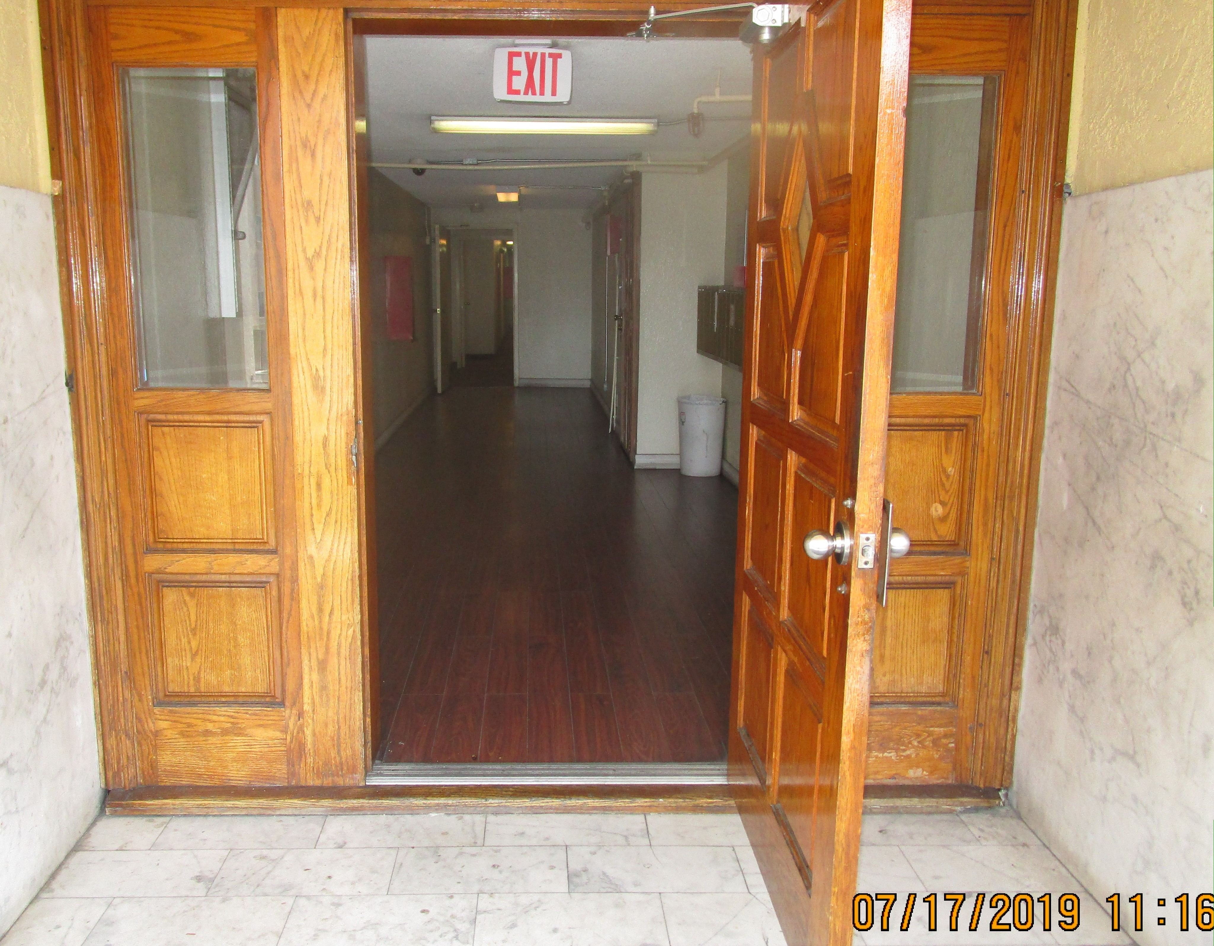 View of an exit, oak wood open door, hallway, brown wood floors.