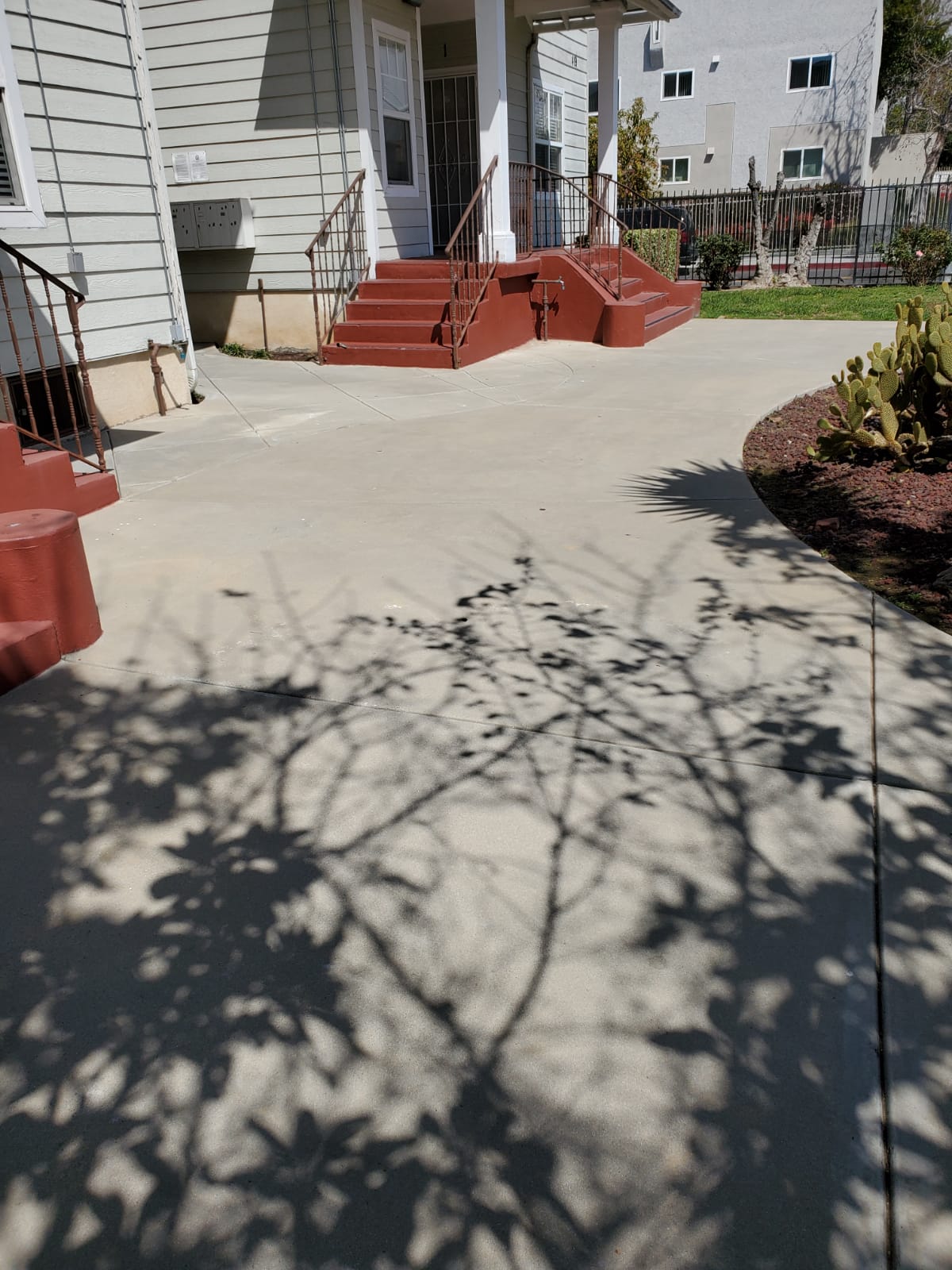 Image of front walkway with landscaping and red stairs to building.