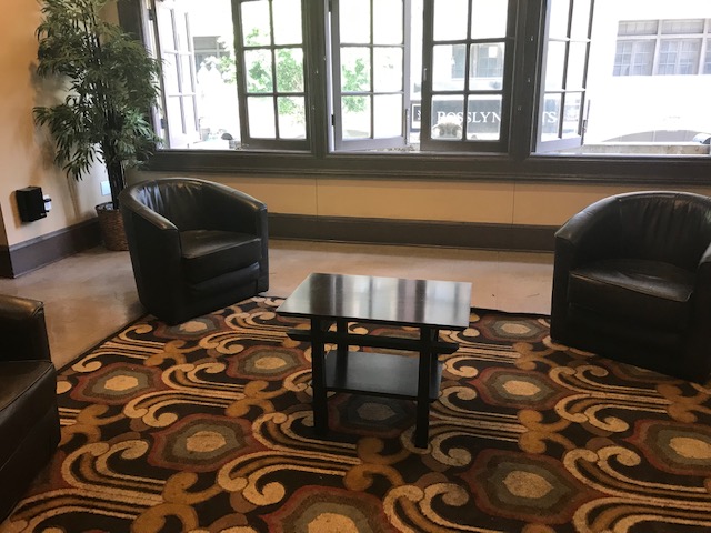 Interior view of the lobby area of the Rosslyn Hotel showing sofa chairs and coffee table on top of a colorful area rug
