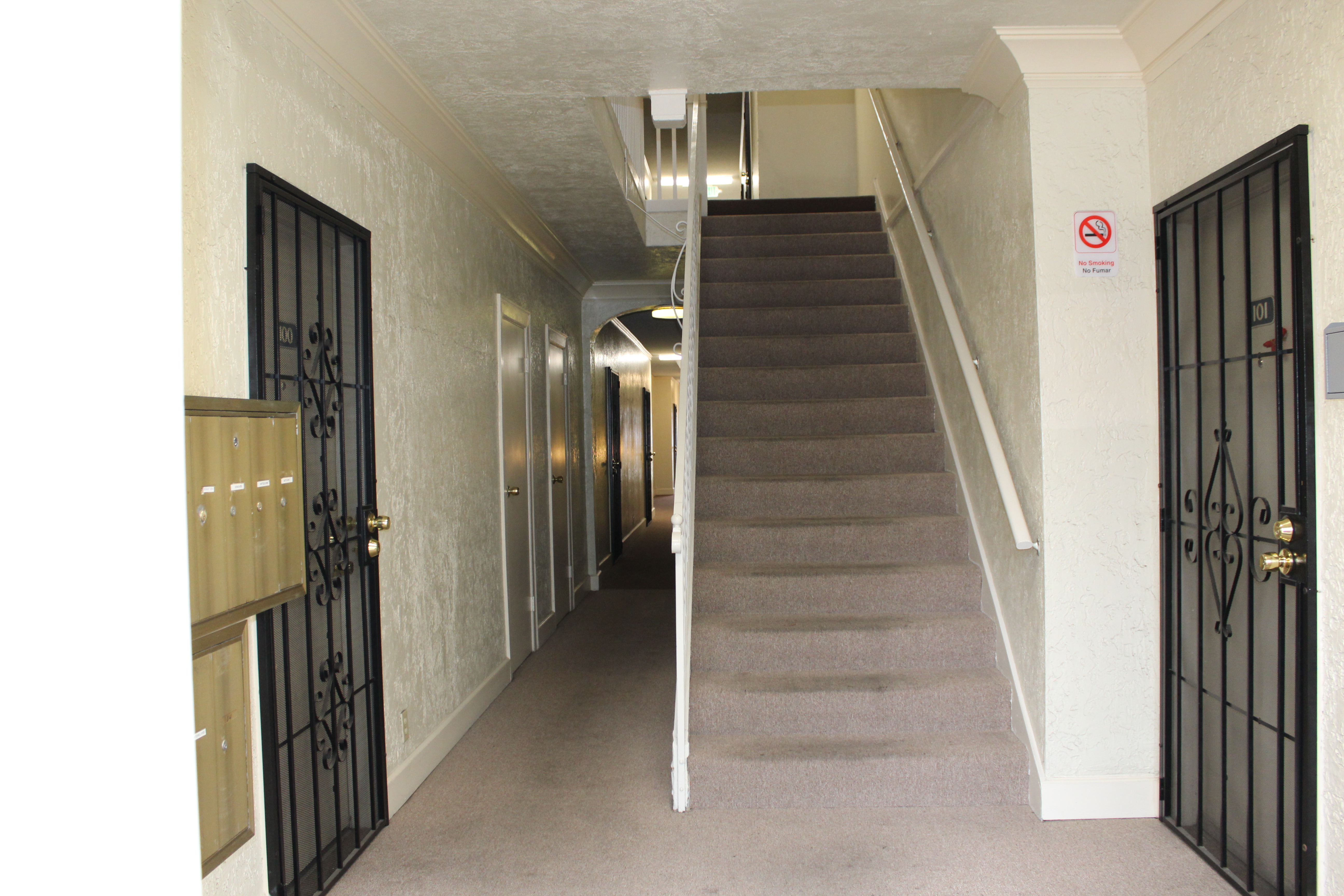 Small lobby area with mailboxes on the right hand side, stairs on the left hand side, and unit doors along the corridor.