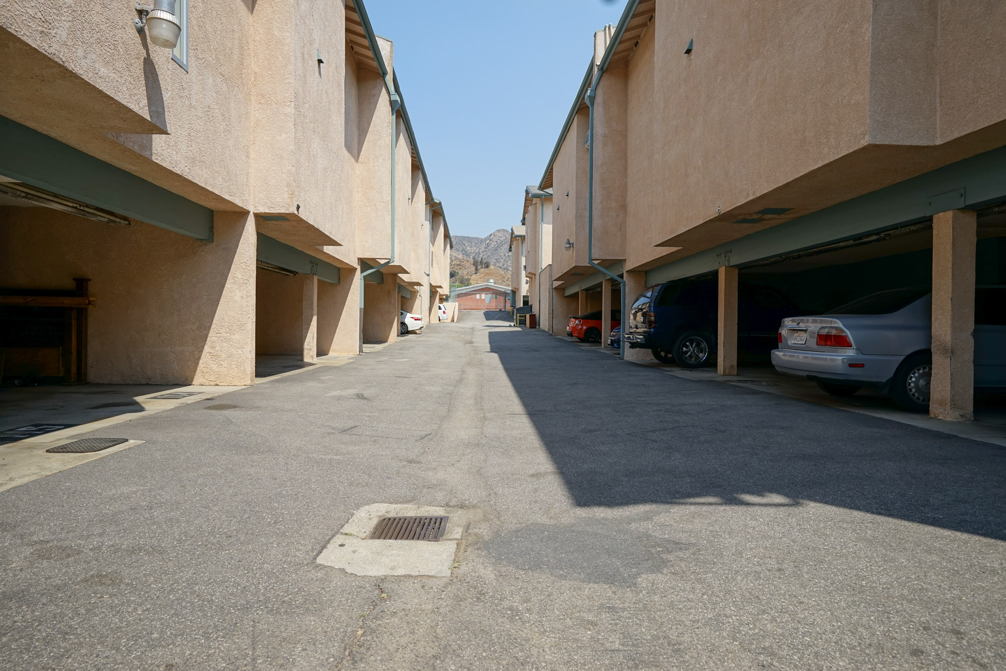 View of a driveway in the center opening of a building. Parking spaces are under the building.
