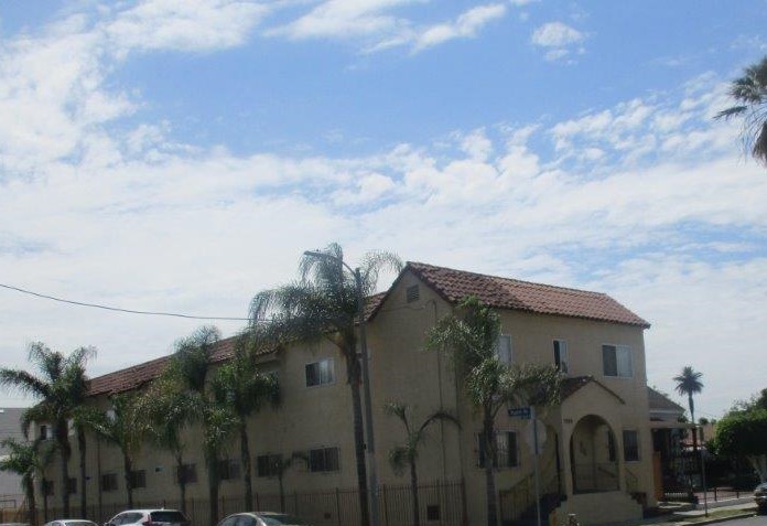 Street view of the two story building with palm trees along the property